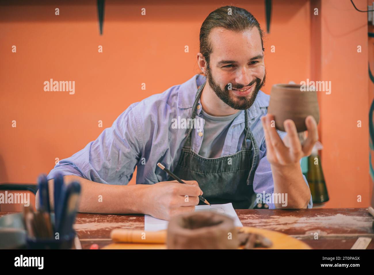 artista di ceramica artigianale soddisfatto del prototipo di laboratorio di produzione di vasi in argilla per piccole e medie imprese Foto Stock