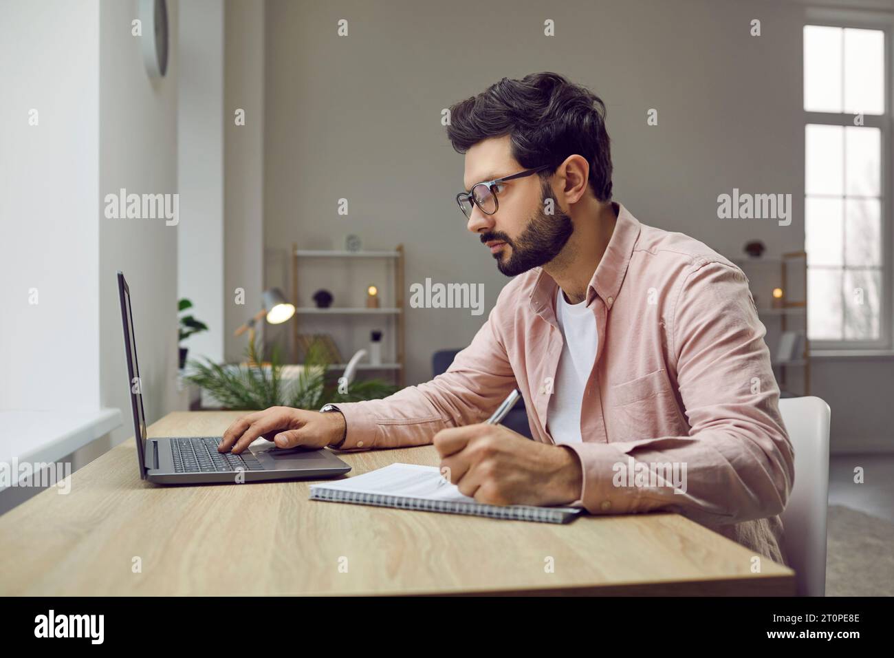 Foto con vista laterale di un giovane che indossa occhiali con un computer portatile Foto Stock