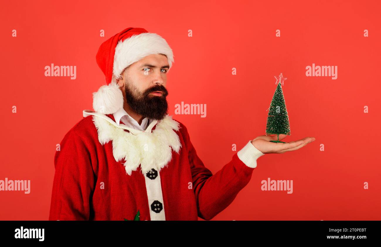 Buon Natale e felice anno nuovo. Babbo Natale con un piccolo abete sulla mano di palma pronto per Natale. Uomo barbuto in costume di Babbo Natale con piccolo Foto Stock