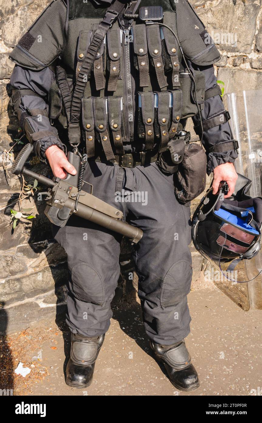 Funzionario di polizia con la maglia caricato con AEPs, e portante una Heckler e Koch L104A1 37mm single-shot AEP launcher Foto Stock