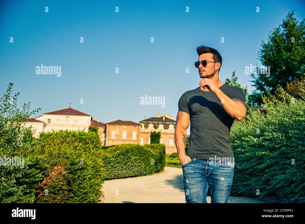 Un uomo in piedi su una strada sterrata con degli alberi sullo sfondo. Foto di un uomo in piedi su una strada sterrata circondata da alberi Foto Stock