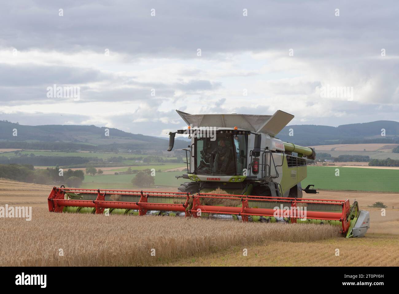 Una mietitrebbia Claas Lexion 8600 per la raccolta di orzo in un Hillside Field affacciato sulla campagna circostante Foto Stock