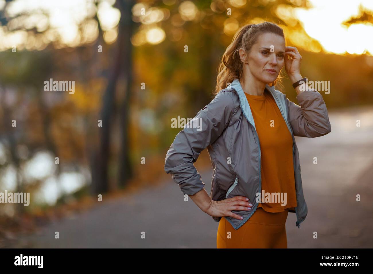 Ciao autunno. elegante donna di mezza età in abiti da fitness nel parco che guarda in lontananza. Foto Stock