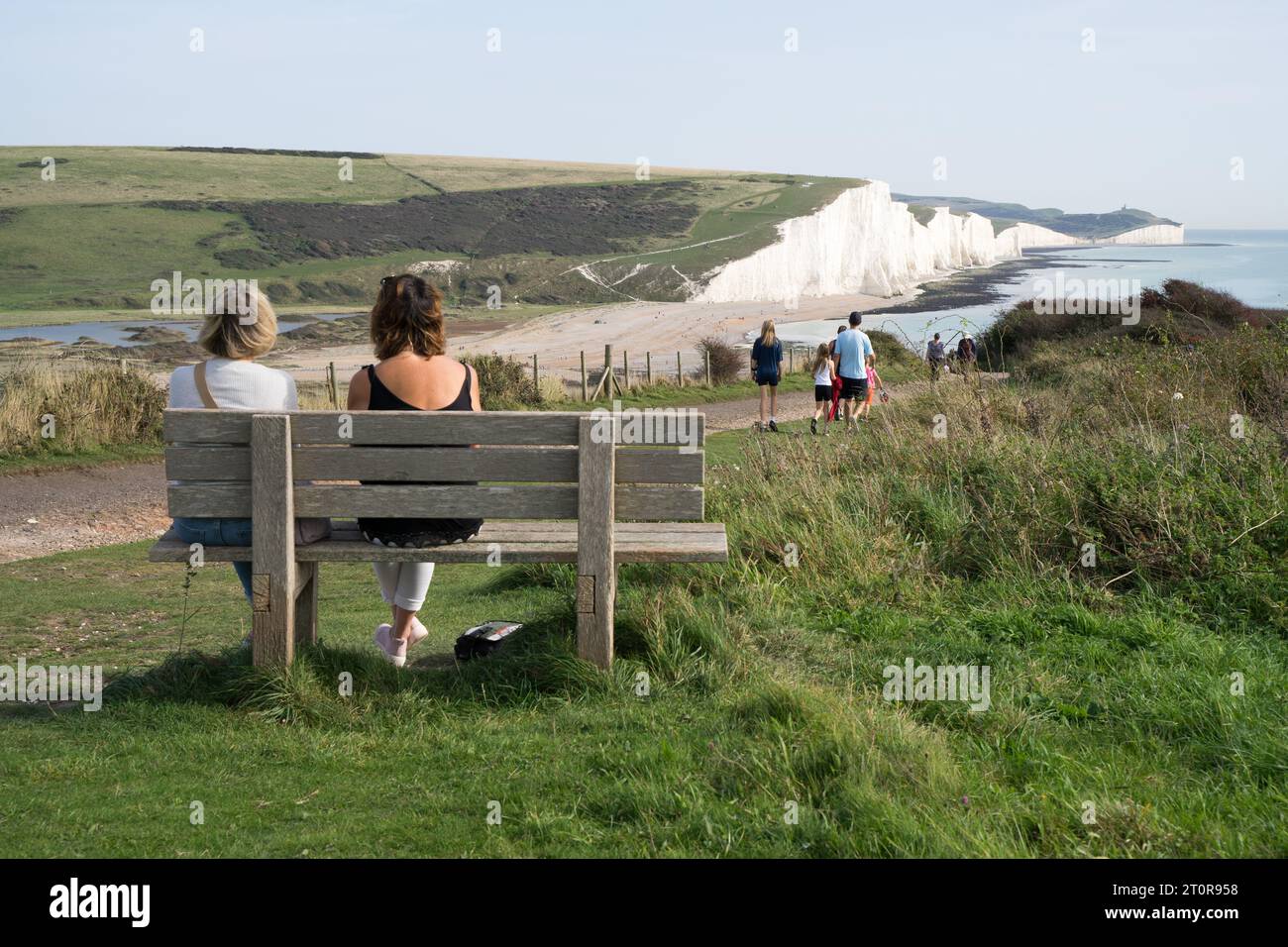 Kent UK, 8 ottobre 2023. Meteo Regno Unito. Due donne sedevano sulla panchina godendosi la vista delle sette scogliere del parco nazionale per immergersi nell'Autumn Sunshine, Kent, Inghilterra, Regno Unito. Credito: Xiu Bao/Alamy Live News Foto Stock