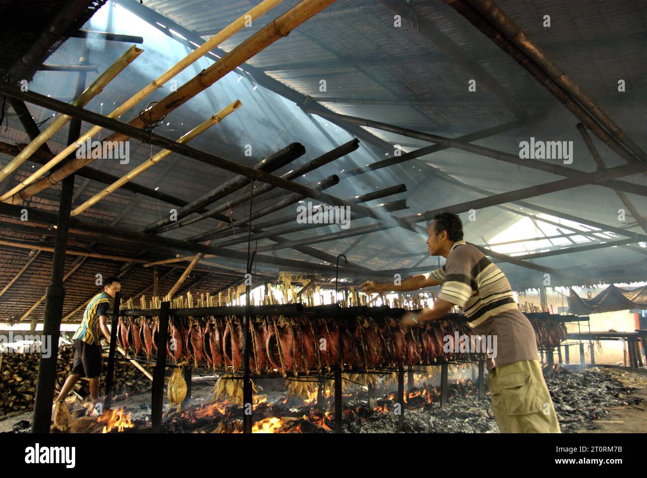 Vista di un laboratorio di produzione di pesce affumicato che utilizza carni di tonno striato presso un'industria domestica a Bitung, Sulawesi settentrionale, Indonesia. I contributi delle conoscenze indigene all'innovazione tecnologica offrono un'ampia gamma di opzioni per la gestione, tra l'altro, della sicurezza alimentare, secondo la relazione del 2023 del gruppo intergovernativo sui cambiamenti climatici (IPCC). Popolarmente noto come cakalang fufu, il tonno affumicato è considerato un alimento esotico indigeno, e potrebbe diventare una soluzione alternativa per affrontare gli impatti del cambiamento climatico sull'oceano. la Banca Mondiale avverte che, oltre agli impatti di... Foto Stock