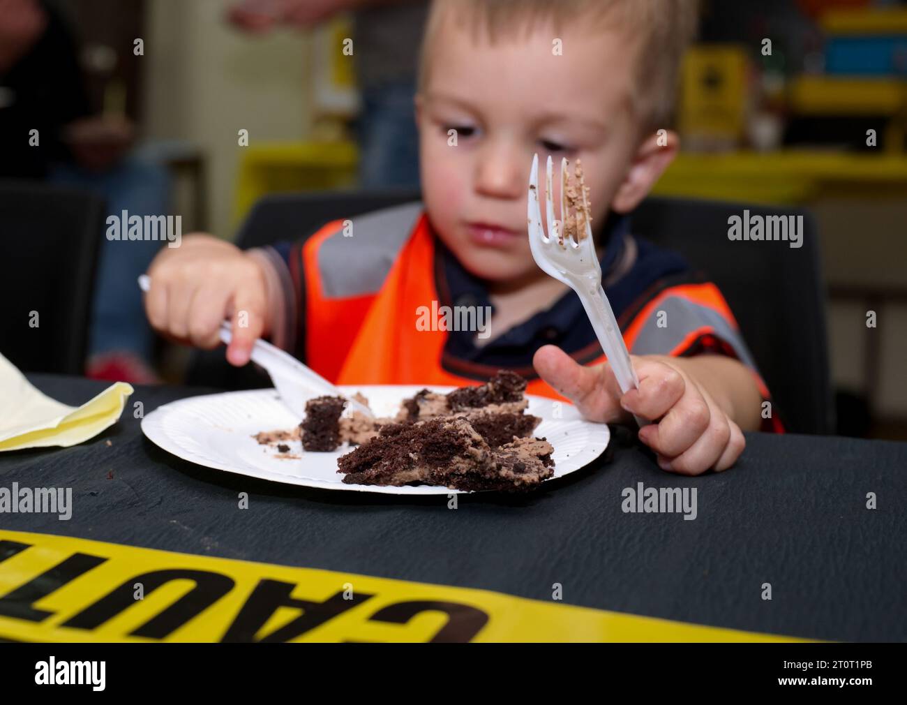 Piccolo bambino seduto al tavolo a mangiare una torta per il suo compleanno Foto Stock