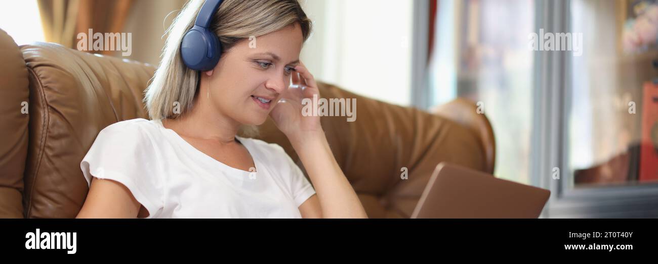 Donna lavora su un computer portatile e ascolta la musica con le cuffie Foto Stock