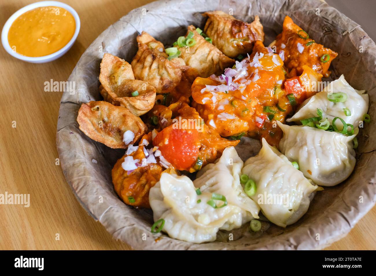 Un piatto di mamme di pollo assortite (gnocchi al vapore, fritti e salsa al peperoncino) servito su un piatto di foglie al Tapari Nights, un ristorante nepalese a Sydney Foto Stock
