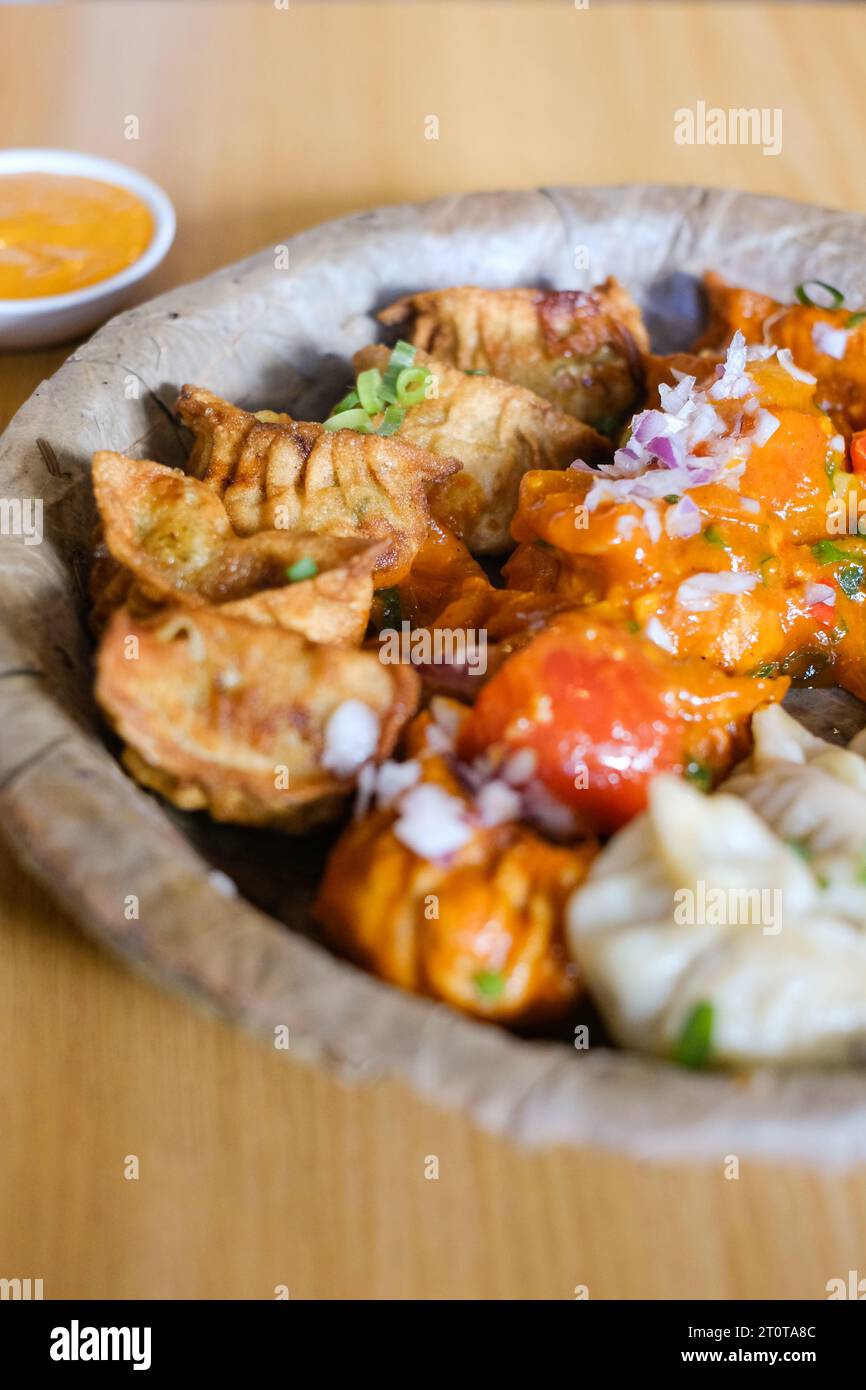 Un piatto di mamme di pollo assortite (gnocchi al vapore, fritti e salsa al peperoncino) servito su un piatto di foglie al Tapari Nights, un ristorante nepalese a Sydney Foto Stock