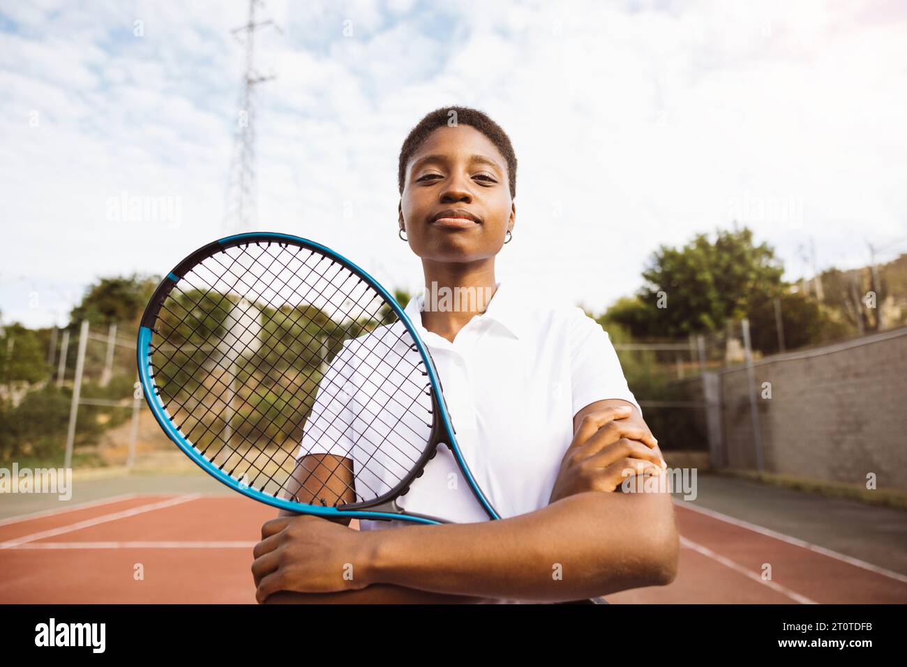 Ritratto di una giovane bella donna con vestiti da tennis e racchetta in un campo da tennis pronto a giocare. Foto Stock