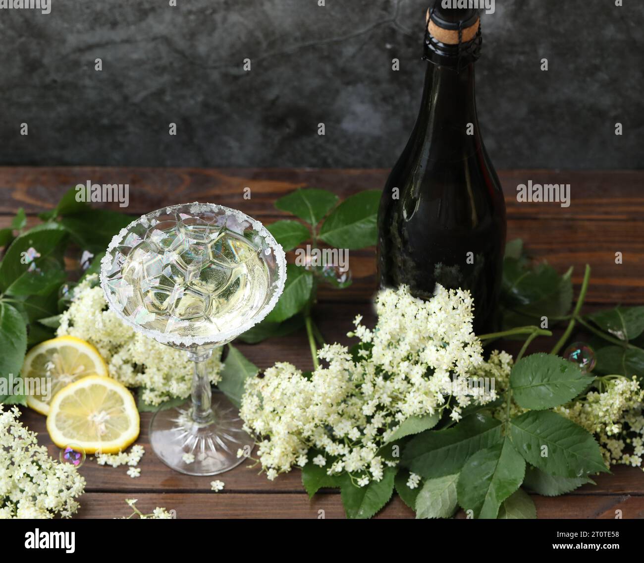 Bicchiere di champagne con liquore ai fiori di sambuco. Decorata con fiori di sambuco bianchi su sfondo naturale Foto Stock