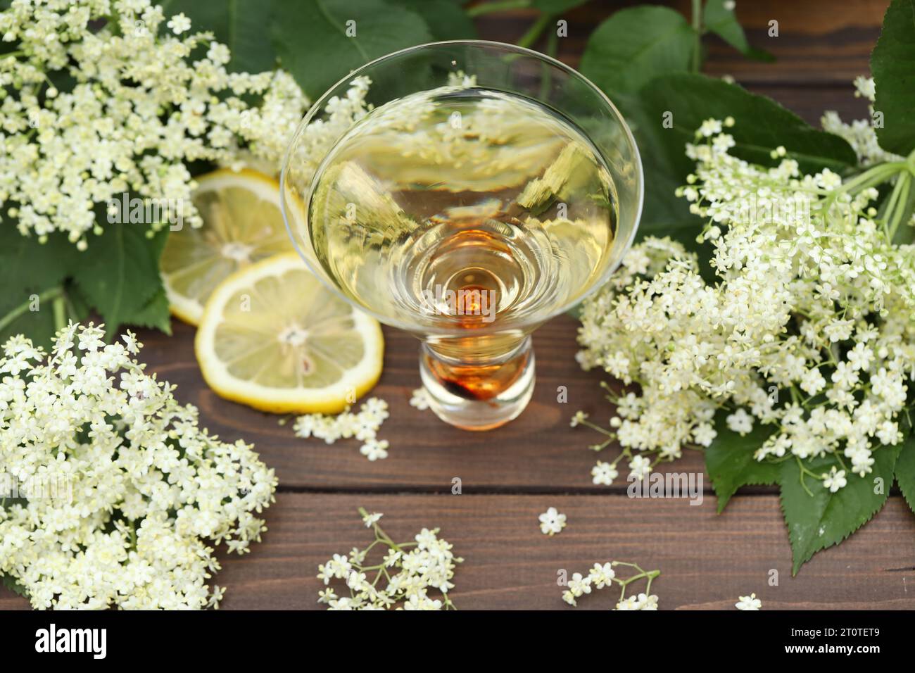 vetro originale con liquore di fiori di sambuco con decorazione di fiori di sambuco su sfondo di legno Foto Stock