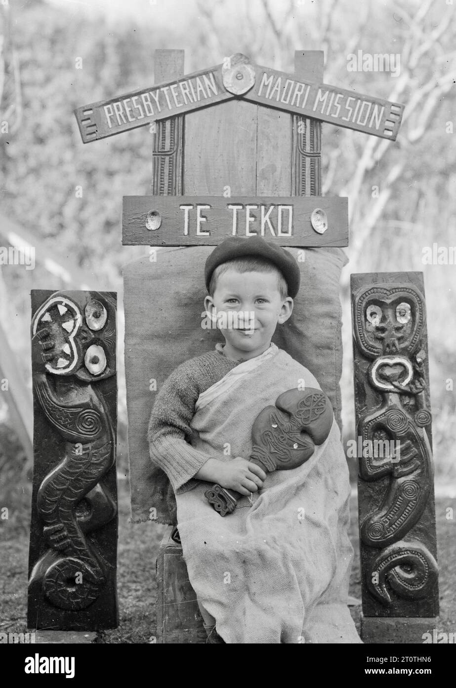Albert Percy Godber (fotografo neozelandese) - nipote Colin, seduto sotto un cartello scolpito per la missione presbiteriana Maori a te Teko - c1938 Foto Stock