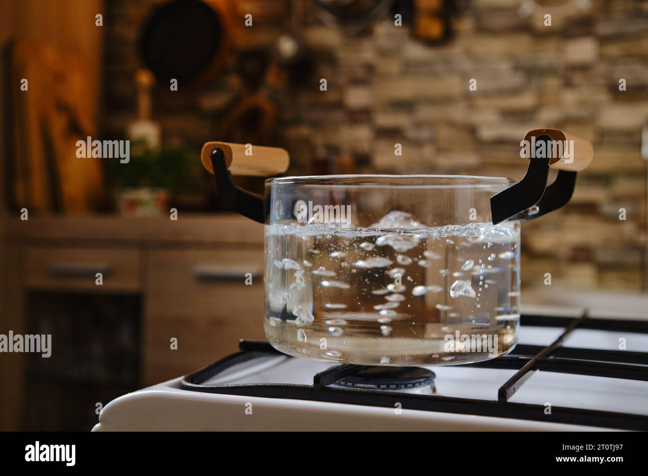 Acqua bollente in pentola di vetro trasparente sul piano cottura Foto stock  - Alamy