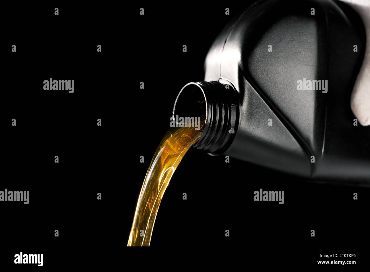 versare olio motore nuovo dalla bottiglia nel motore dell'auto. isolato su sfondo nero Foto Stock