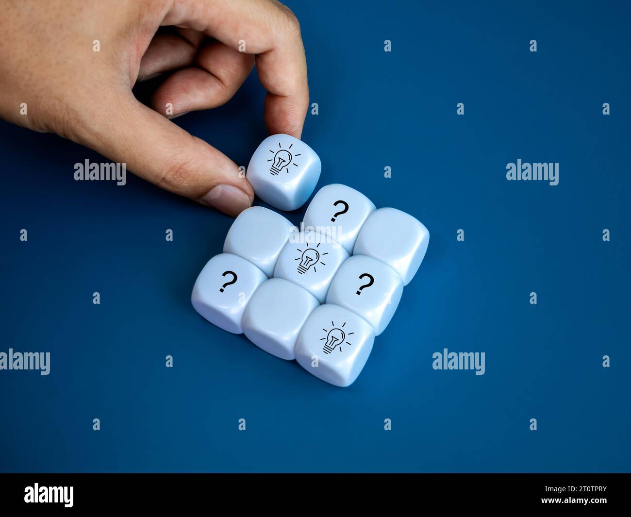 Soluzioni aziendali e concetti di marketing creativi. Icona a forma di lampadina sul blocco cubico bianco in mano con simbolo della domanda sul problema in blu Foto Stock
