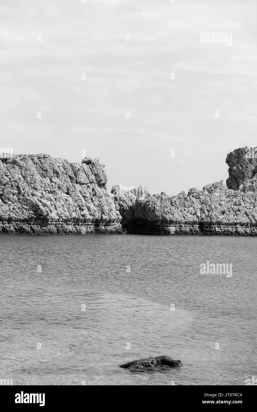 Vista della collina di formazione rocciosa della spiaggia di Saint Paul's Bay nelle acque dell'oceano in bianco e nero Foto Stock