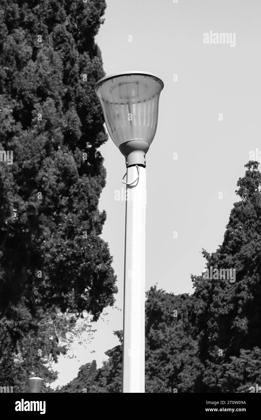 Palo per illuminazione stradale con lampada a lanterna storta in bianco e nero. Sorgente luminosa Foto Stock