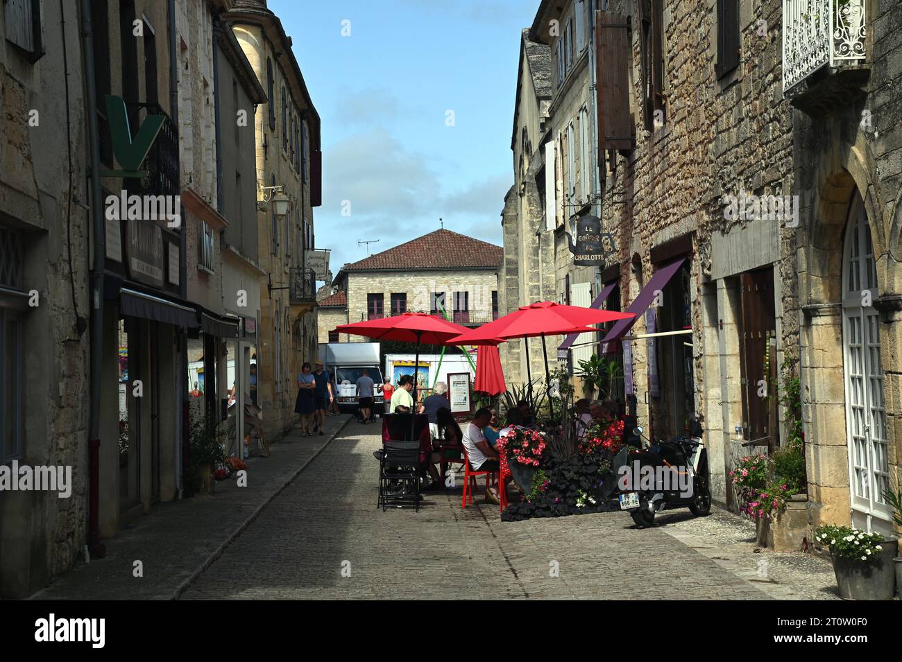 Un piccolo caffè che occupa metà di una strada stretta nella città bastide di Villefranche du Périgord. In estate molti caffè francesi si riversano sulla strada. Foto Stock