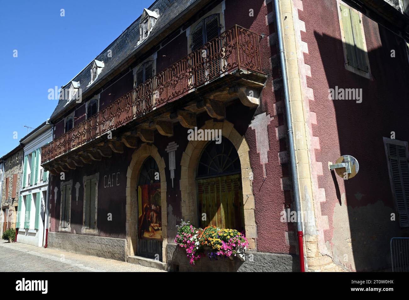 Un edificio abbandonato in una strada nella città di Villefranche du Perigord, Dordogna. Una scena è stata dipinta su una porta per sembrare un caffè. Foto Stock