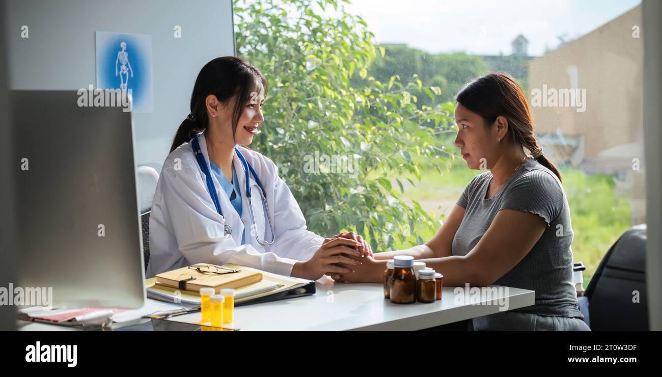 Dottore che dà speranza. Ripresa ravvicinata di una giovane medico che si piega in avanti a una paziente sorridente che tiene la mano nei palmi. Donna custode dentro Foto Stock