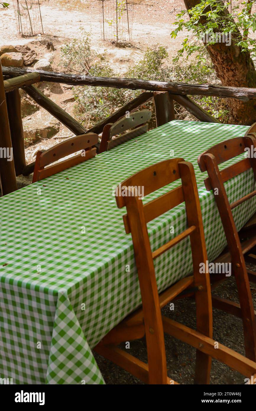 Tavolino geometrico a scacchi verde su un tavolo da picnic e sedie di legno in un ristorante all'aperto nella natura Foto Stock