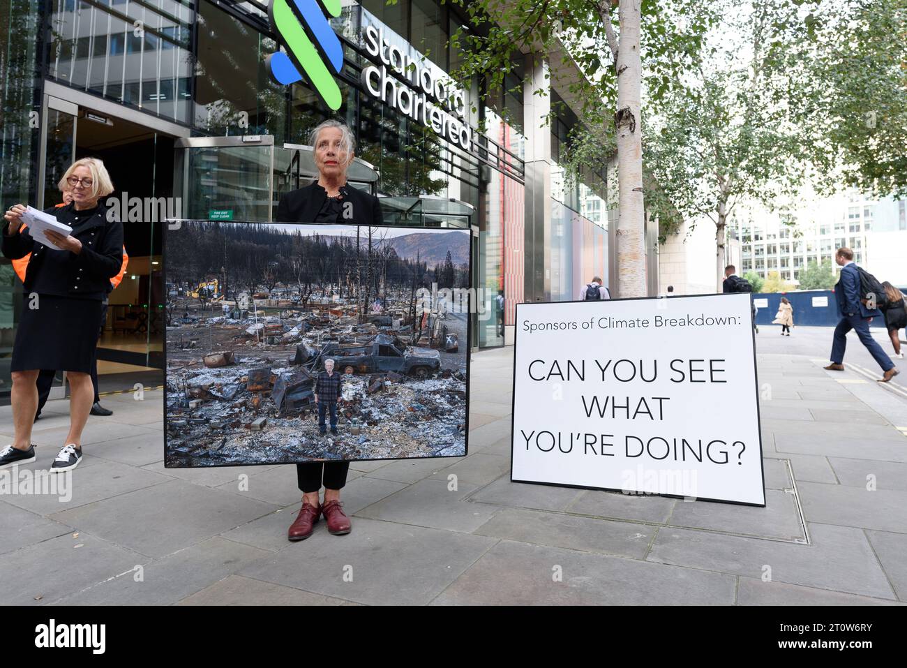 Londra, Regno Unito. 9 ottobre 2023. Mostra di protesta pop-up di immagini delle conseguenze di incendi boschivi del fotografo Gideon Mendel esposte fuori dalla Standard Chartered Bank, uno dei principali finanziatori dei combustibili fossili che, secondo gli scienziati, aumentano la probabilità, la durata e la gravità di tali incendi. L'evento, organizzato da Money Rebellion, è stato programmato in coincidenza con il concorso "fotografo meteorologico dell'anno" della Royal Meteorological Society, sponsorizzato da Standard Chartered. Crediti: Ron Fassbender/Alamy Live News Foto Stock