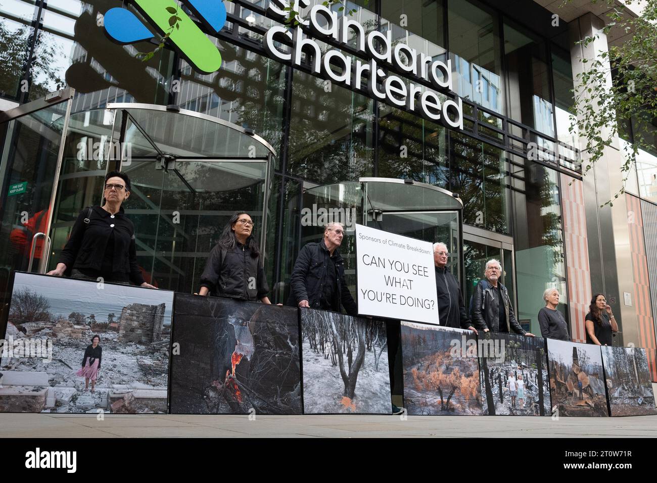 Londra, Regno Unito. 9 ottobre 2023. Mostra di protesta pop-up di immagini delle conseguenze di incendi boschivi del fotografo Gideon Mendel esposte fuori dalla Standard Chartered Bank, uno dei principali finanziatori dei combustibili fossili che, secondo gli scienziati, aumentano la probabilità, la durata e la gravità di tali incendi. L'evento, organizzato da Money Rebellion, è stato programmato in coincidenza con il concorso "fotografo meteorologico dell'anno" della Royal Meteorological Society, sponsorizzato da Standard Chartered. Crediti: Ron Fassbender/Alamy Live News Foto Stock