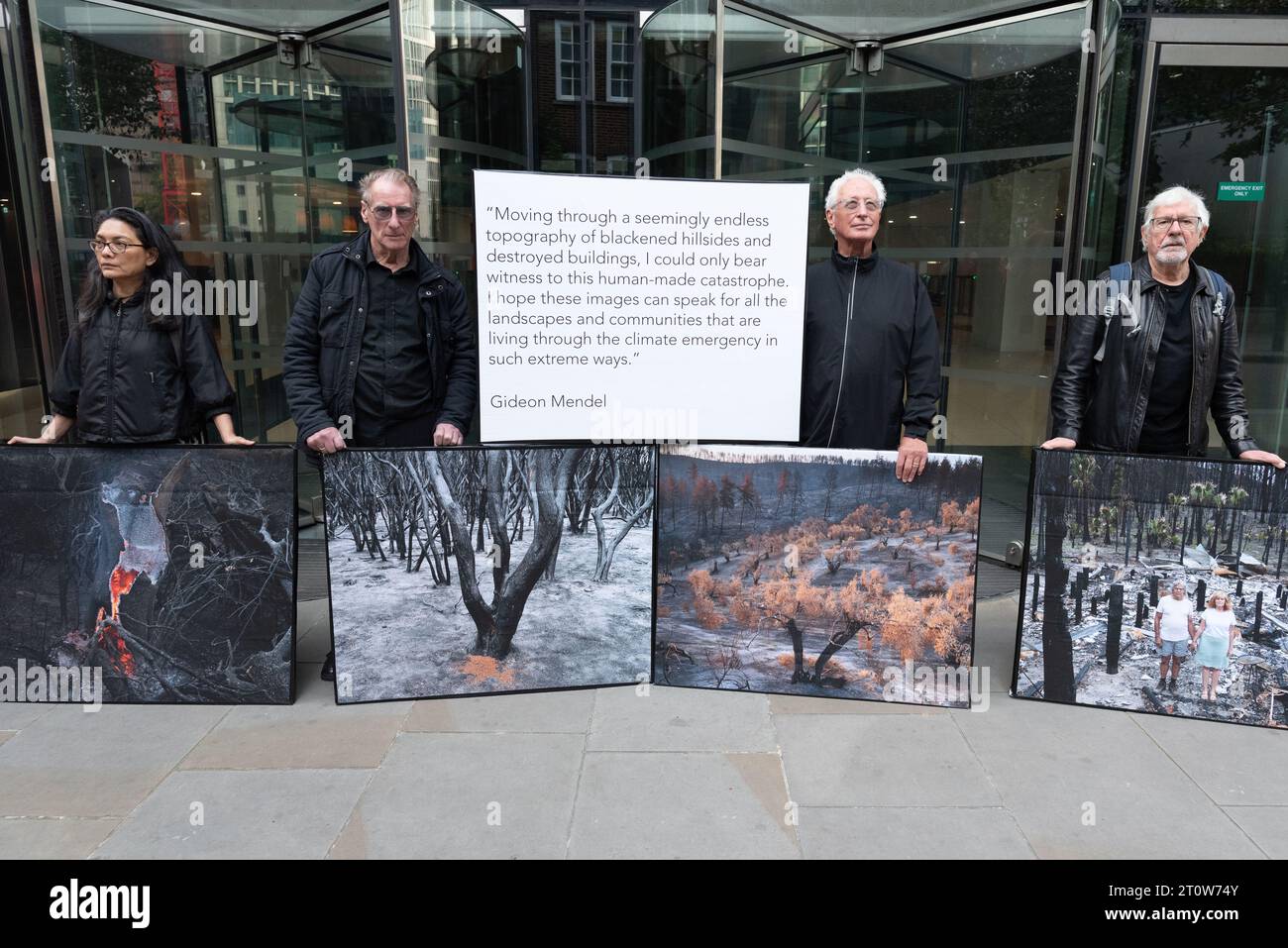 Londra, Regno Unito. 9 ottobre 2023. Mostra di protesta pop-up di immagini delle conseguenze di incendi boschivi del fotografo Gideon Mendel esposte fuori dalla Standard Chartered Bank, uno dei principali finanziatori dei combustibili fossili che, secondo gli scienziati, aumentano la probabilità, la durata e la gravità di tali incendi. L'evento, organizzato da Money Rebellion, è stato programmato in coincidenza con il concorso "fotografo meteorologico dell'anno" della Royal Meteorological Society, sponsorizzato da Standard Chartered. Crediti: Ron Fassbender/Alamy Live News Foto Stock