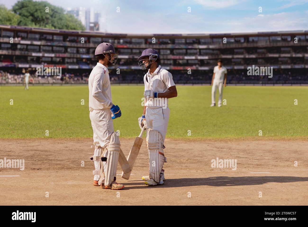 Due batsmen che hanno una conferenza a metà wicket sul campo durante una partita di cricket Foto Stock