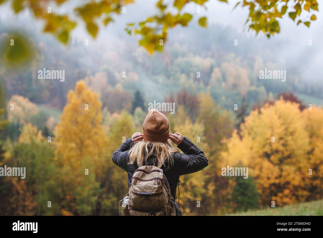 Escursioni autunnali. La donna indossa un cappello a maglia durante l'escursione nella foresta montana con il freddo nebbia Foto Stock