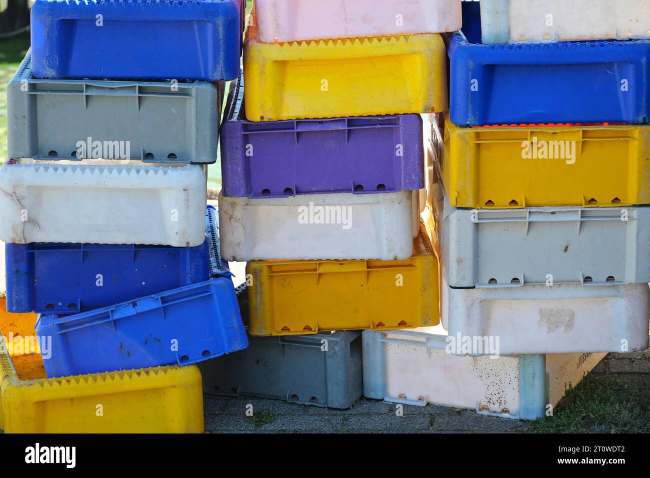 Pila di casse di plastica in blu, giallo e bianco per il trasporto e la vendita di pesce sul mercato nel porto di pesca, concetto commerciale e industriale Foto Stock