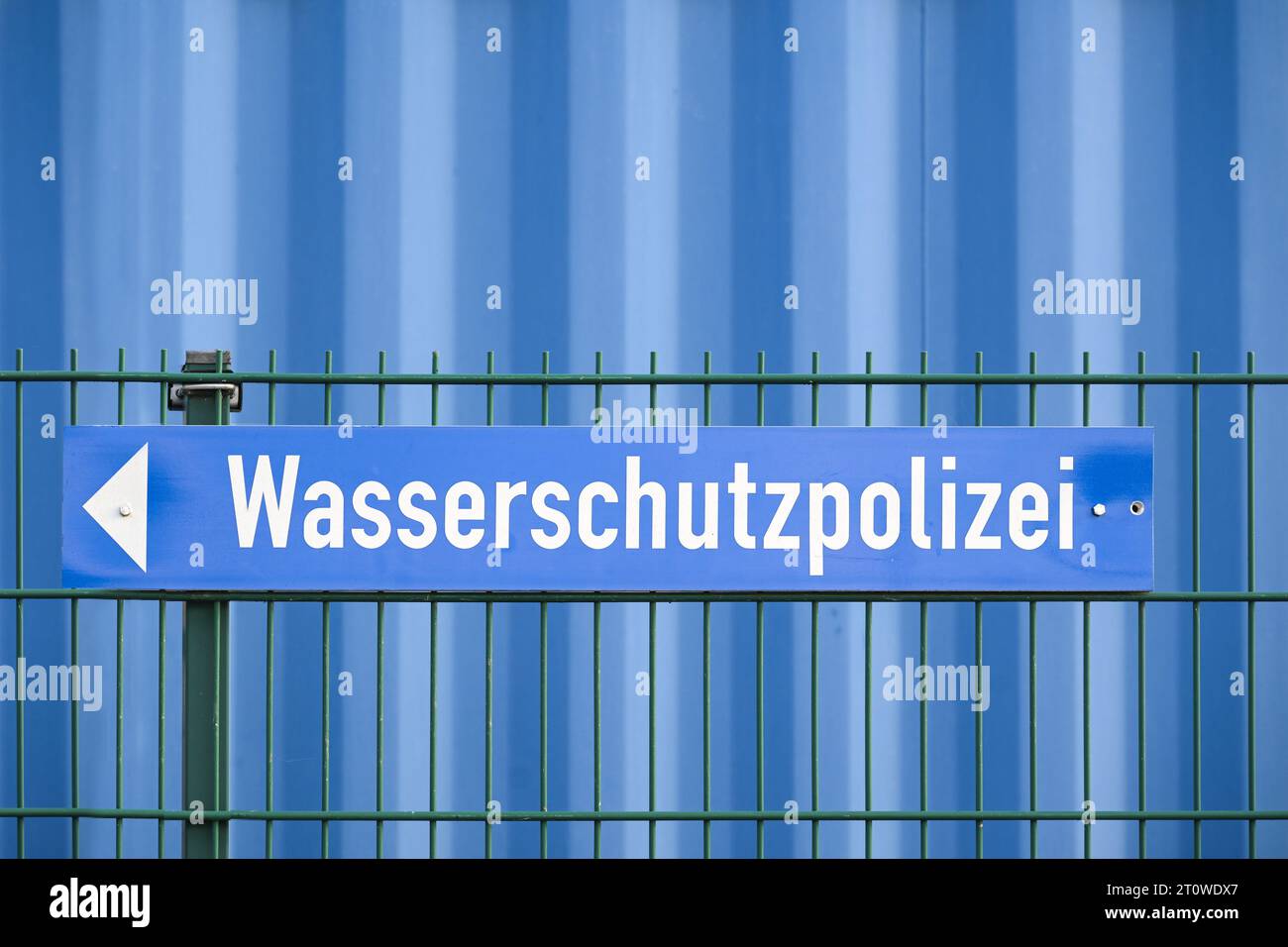 Firma con la parola tedesca Wasserschutzpolizei che significa polizia di protezione dell'acqua su una recinzione di fronte a un muro blu, spazio copia, fuoco selezionato Foto Stock