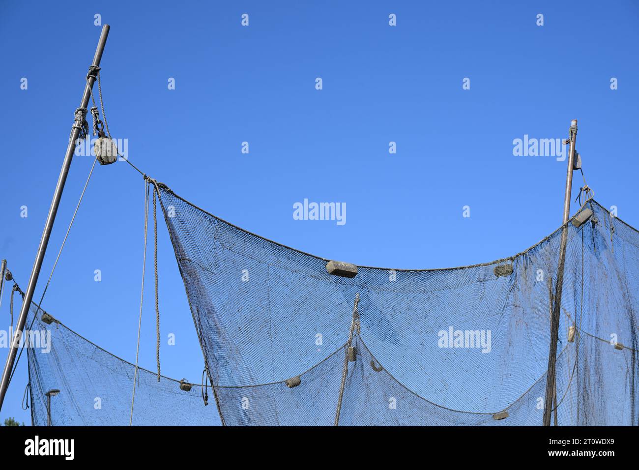 Appendere reti da pesca contro un cielo azzurro in un porto sul Mar Baltico, concetto per vacanze marittime e industria della pesca, spazio copia, selezionato Foto Stock