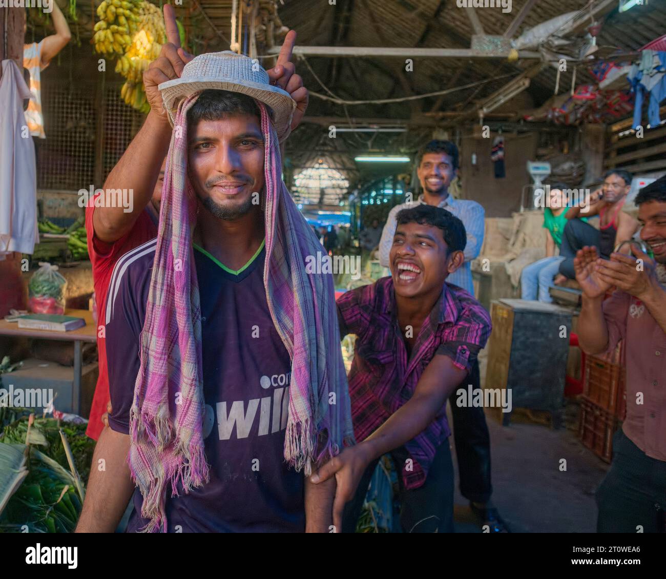 Giovani dipendenti maschi in un mercato di Mangalore (Mangaluru), Karnataka, India meridionale, che si godono un po' di clownery e si divertono Foto Stock