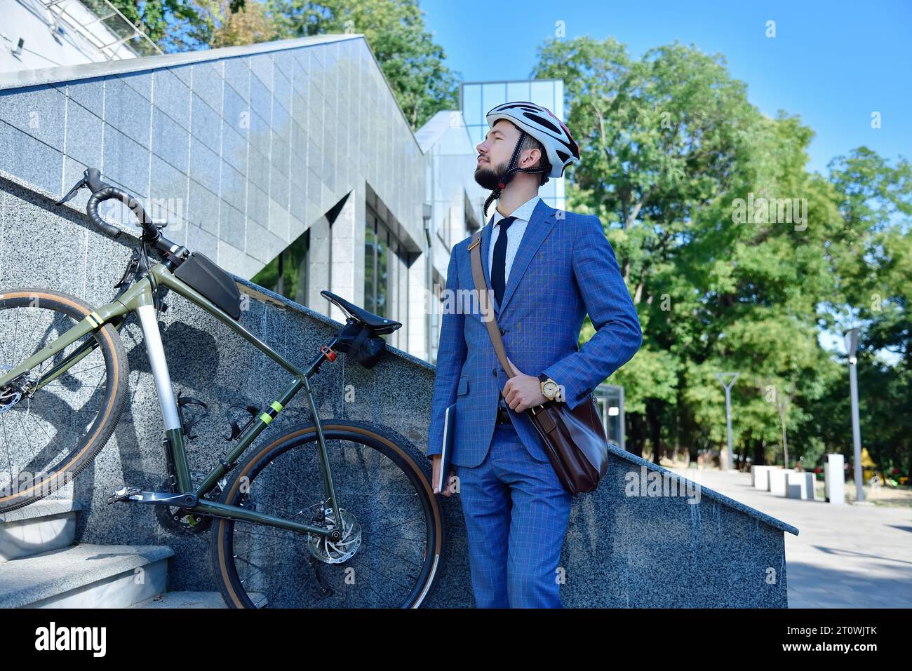 Uomo d'affari barbuto con tablet digitale in piedi vicino al business center. Concetto aziendale e ambientale dei trasporti. Foto Stock