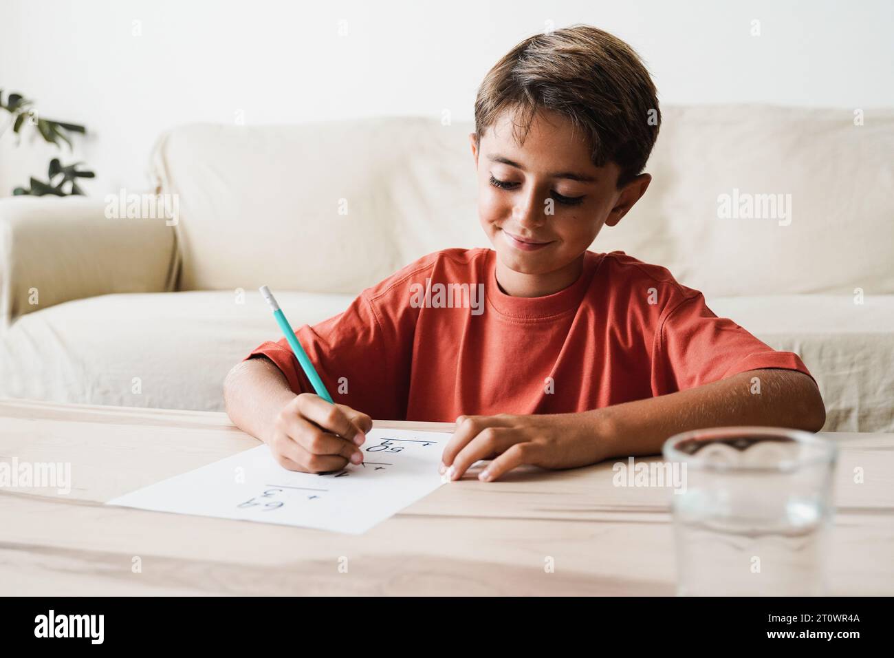 Istruzione a casa. Felice bambino latino che studia per il progetto di matematica. Concentrati sulla faccia Foto Stock