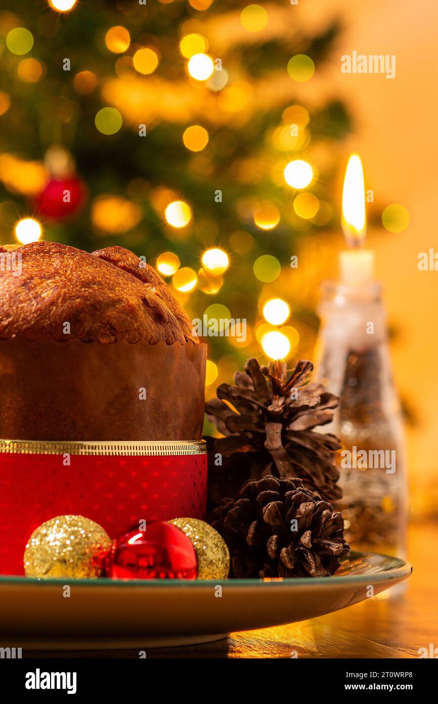 Goiânia, Goias, Brasile – 8 ottobre 2023: Panettone, coni di pino, candele accese, palle e albero di Natale sullo sfondo con luci bokeh. Foto Stock