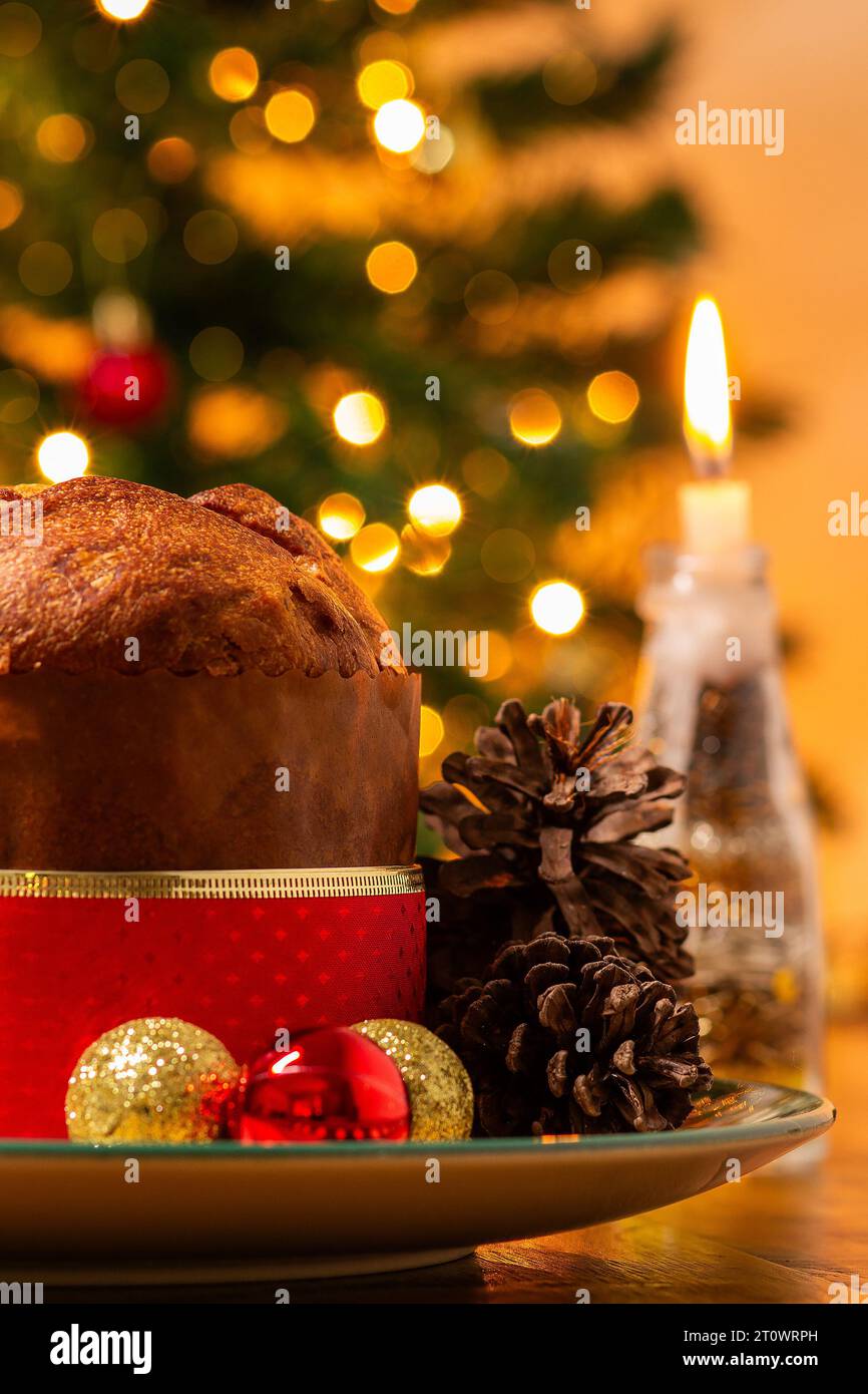 Goiânia, Goias, Brasile – 8 ottobre 2023: Panettone, coni di pino, candele accese, palle e albero di Natale sullo sfondo con luci bokeh. Foto Stock