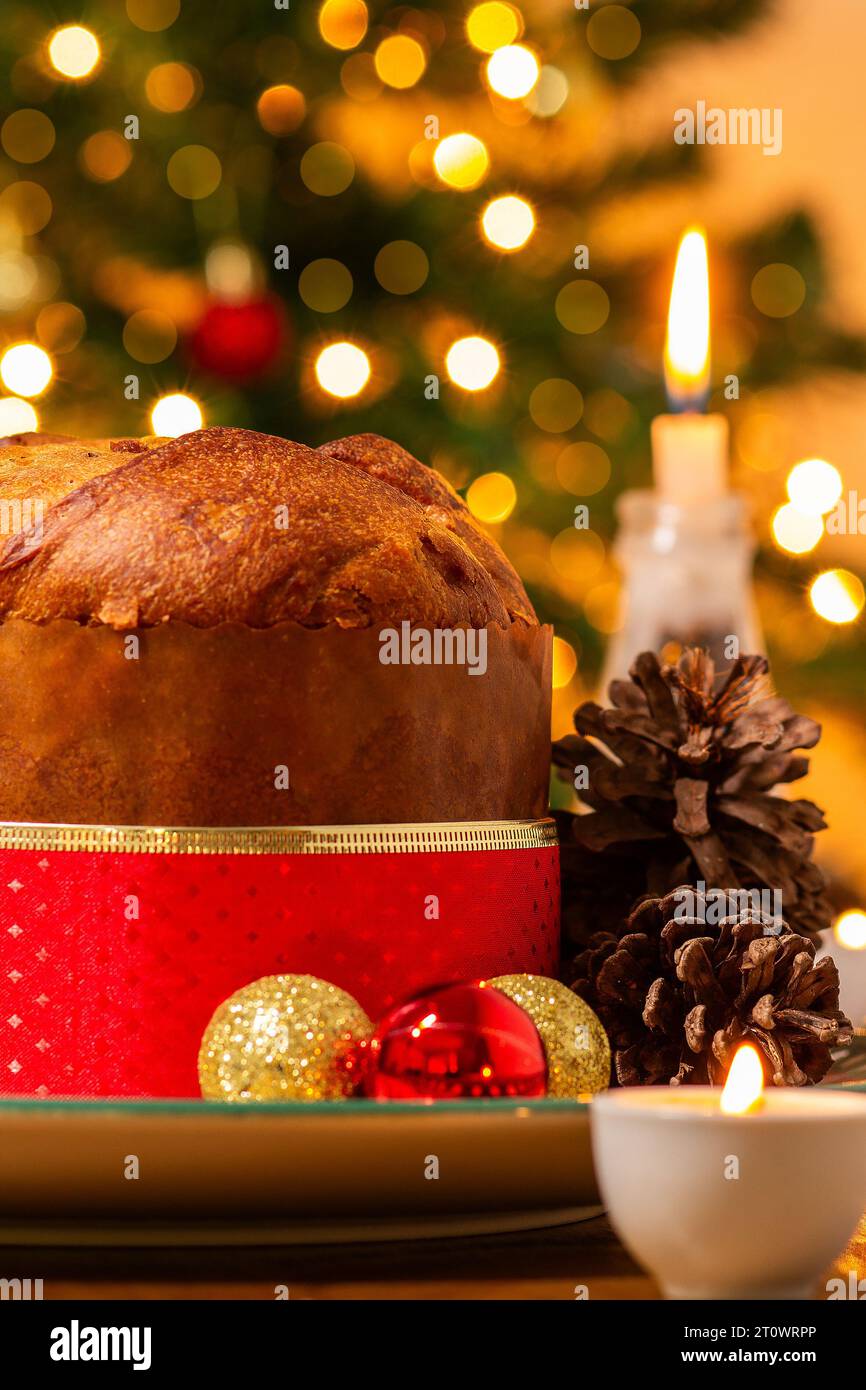 Goiânia, Goias, Brasile – 8 ottobre 2023: Panettone, coni di pino, candele accese, palle e albero di Natale sullo sfondo con luci bokeh. Foto Stock