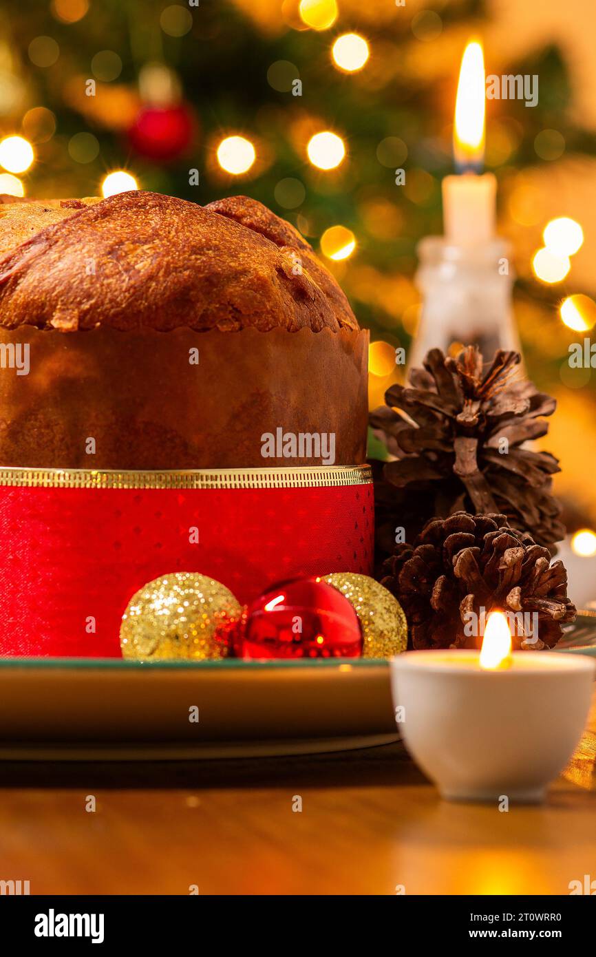 Goiânia, Goias, Brasile – 8 ottobre 2023: Panettone, coni di pino, candele accese, palle e albero di Natale sullo sfondo con luci bokeh. Foto Stock