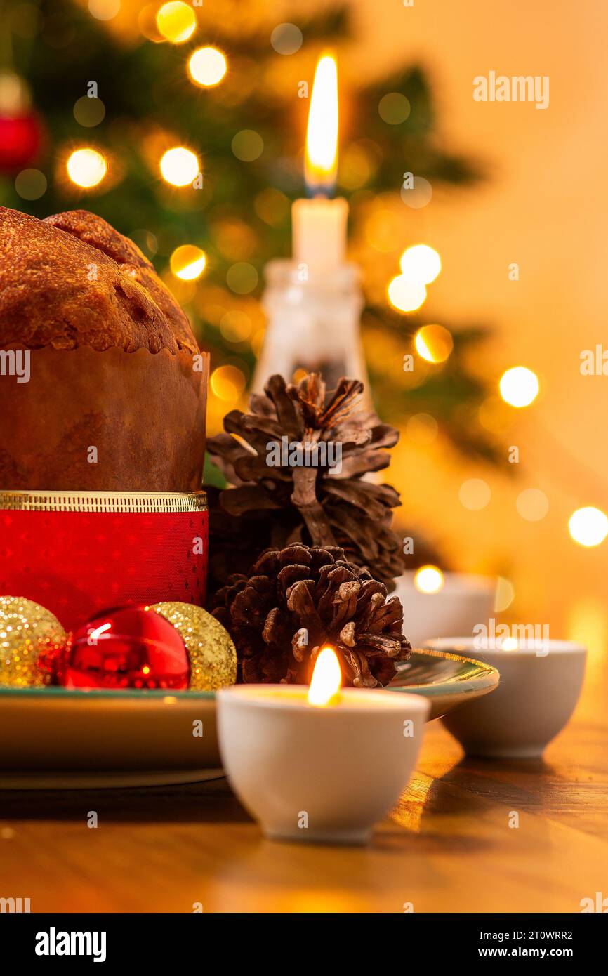 Goiânia, Goias, Brasile – 8 ottobre 2023: Panettone, coni di pino, candele accese, palle e albero di Natale sullo sfondo con luci bokeh. Foto Stock