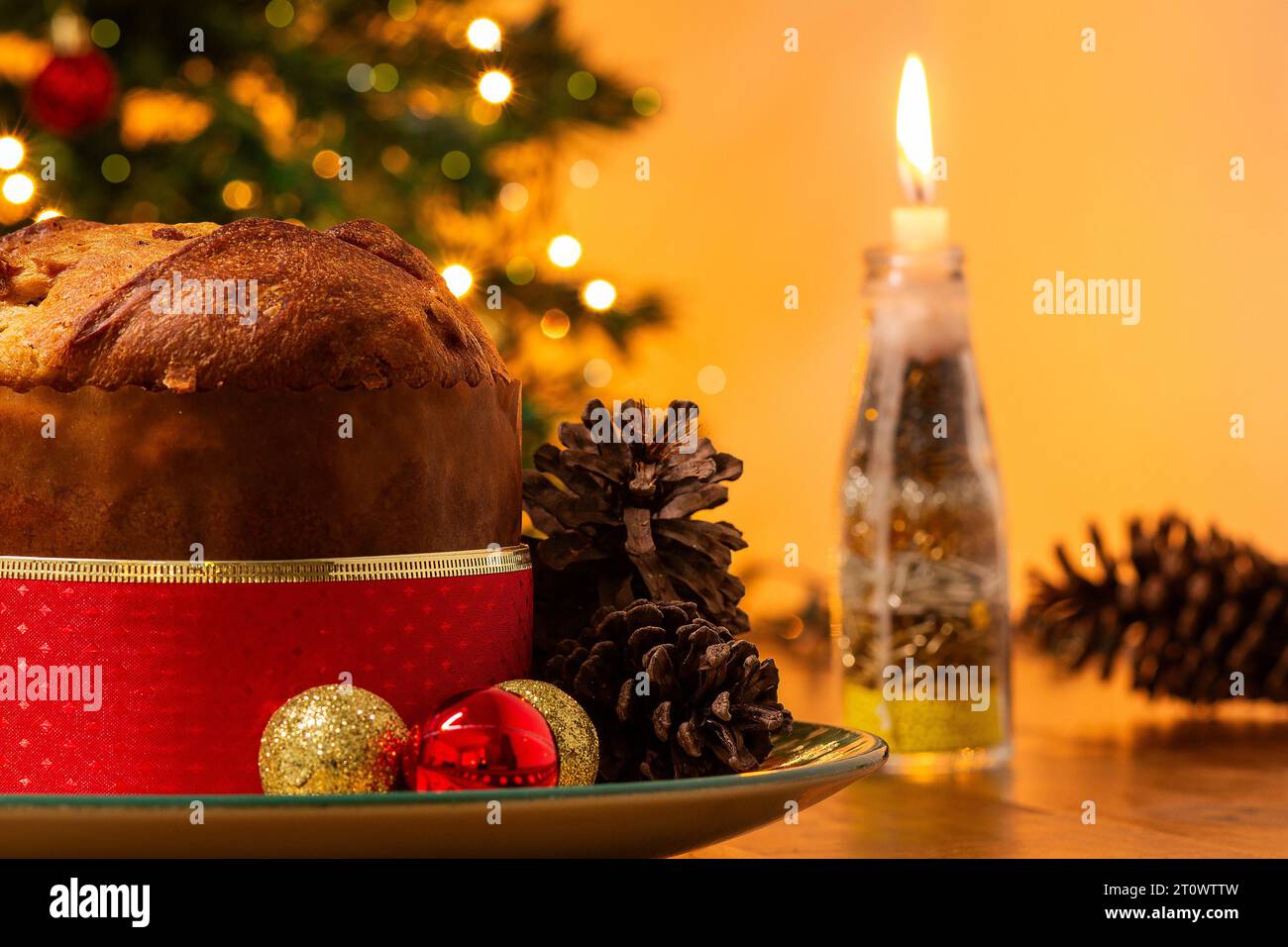 Goiânia, Goias, Brasile – 8 ottobre 2023: Panettone, coni di pino, candele accese, palle e albero di Natale sullo sfondo con luci bokeh. Foto Stock