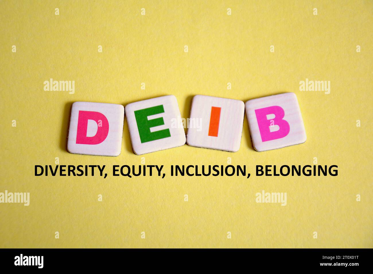 Lettere colorate DEIB su tessere e parole: Diversità, equità, inclusione e appartenenza su sfondo giallo. Concetto aziendale di DEIB. Foto Stock