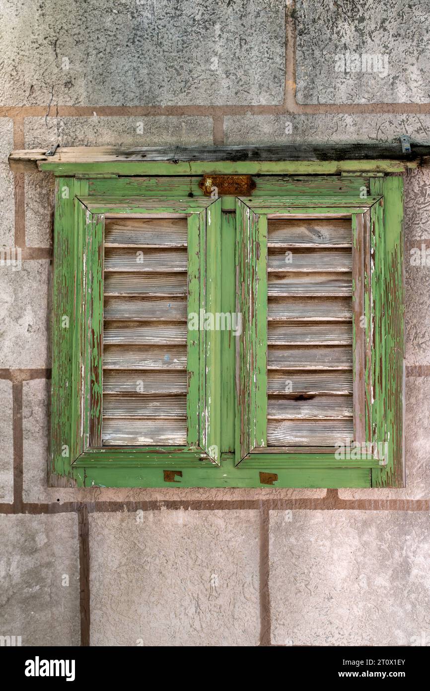 Una vecchia finestra con cornice verde e diaframmi intemprati Foto Stock