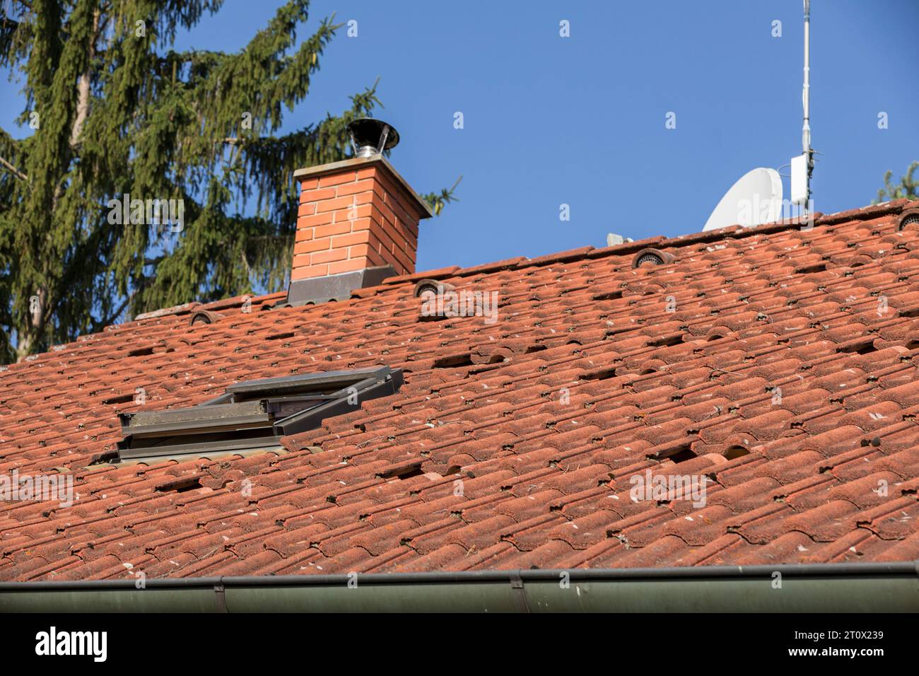 il tetto di una casa di famiglia con piastrelle rosse, sacchetti rossi sul tetto della casa pronti per impianti fotovoltaici, installazione di pannelli fotovoltaici Foto Stock