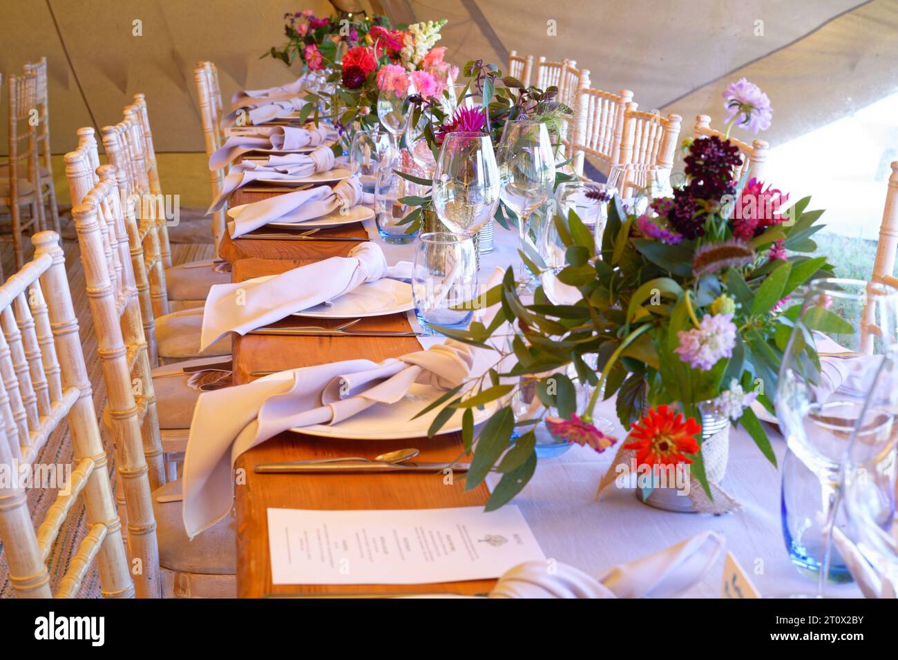 Tendone per matrimoni decorato e pronto per l'arrivo degli ospiti. Tavoli, sedie, fiori e ambientazioni. Una tenda rustica dal design teepee. Foto Stock