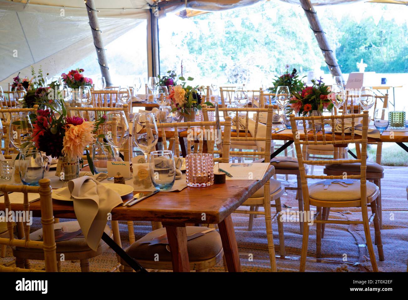 Tendone per matrimoni decorato e pronto per l'arrivo degli ospiti. Tavoli, sedie, fiori e ambientazioni. Una tenda rustica dal design teepee. Foto Stock