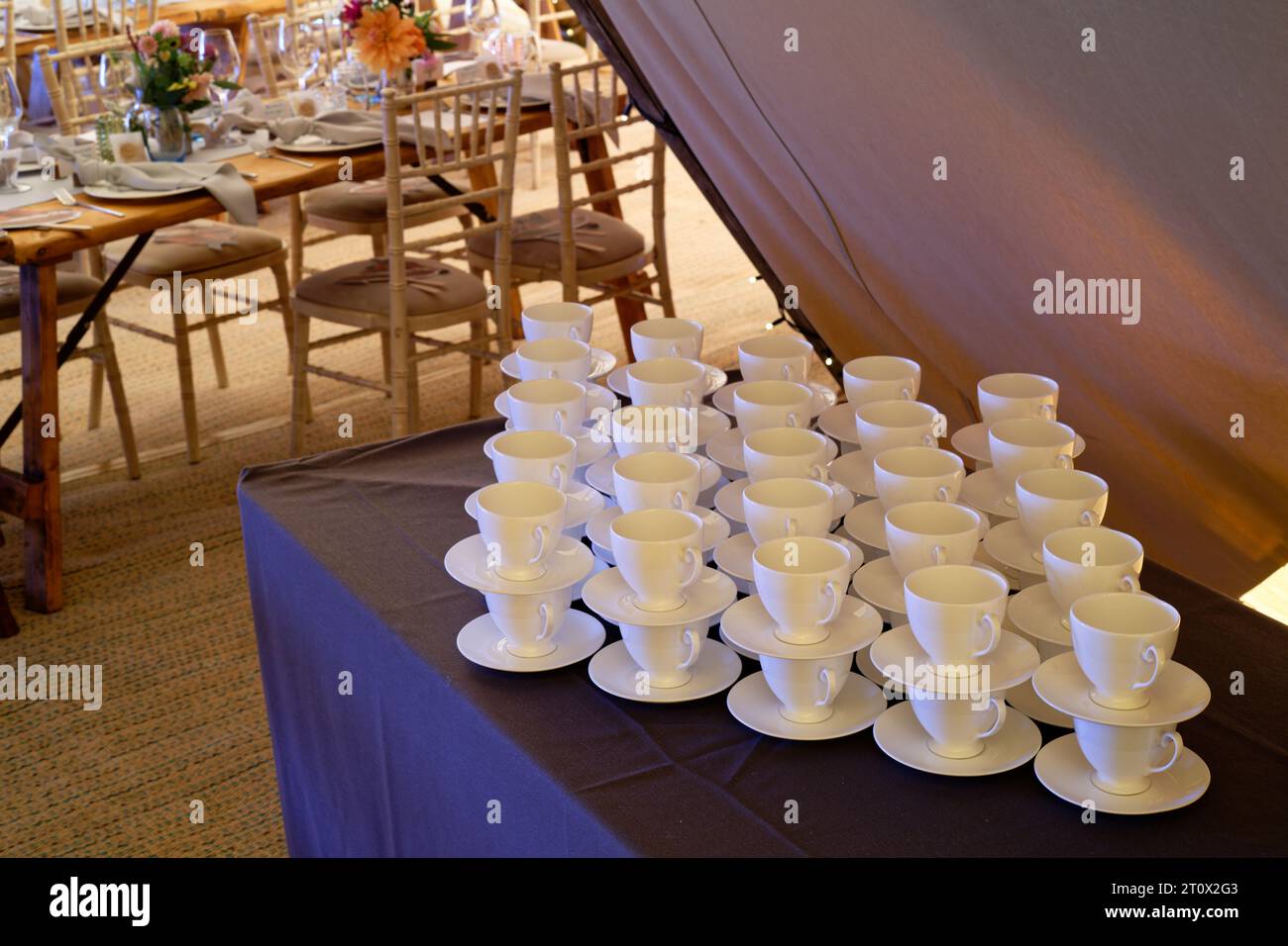 Tendone per matrimoni decorato e pronto per l'arrivo degli ospiti. Tavoli, sedie, fiori e ambientazioni. Una tenda rustica dal design teepee. Foto Stock