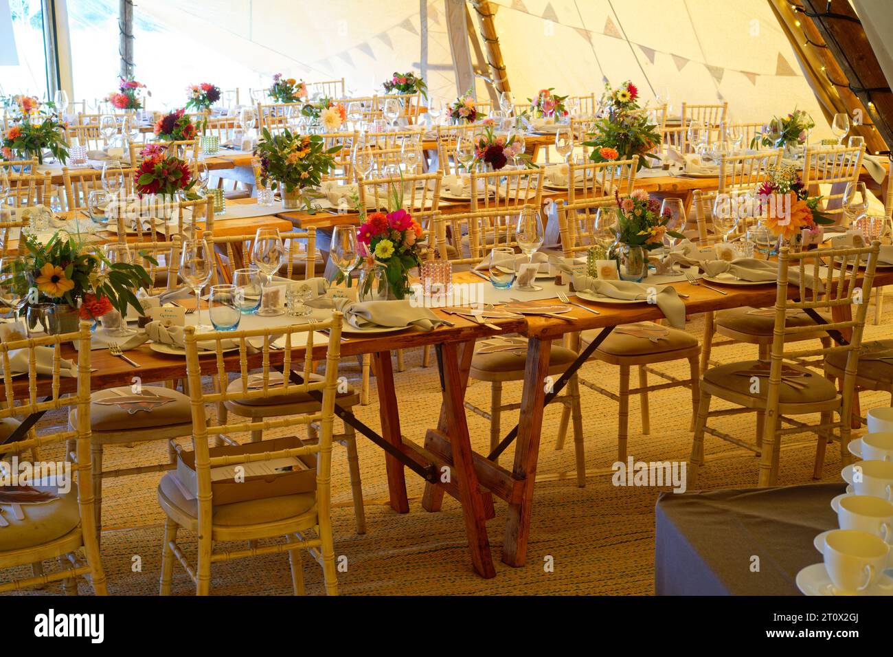 Tendone per matrimoni decorato e pronto per l'arrivo degli ospiti. Tavoli, sedie, fiori e ambientazioni. Una tenda rustica dal design teepee. Foto Stock